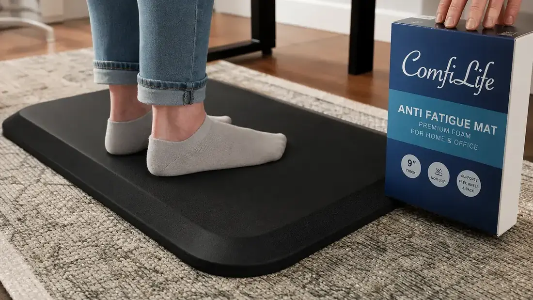 Close-up of a person's feet in socks standing on a thick black ComfiLife anti-fatigue mat next to a standing desk